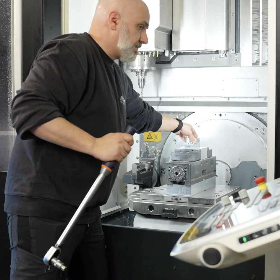 Mitarbeiter richtet ein Werkstück in der Fräsmaschine ein